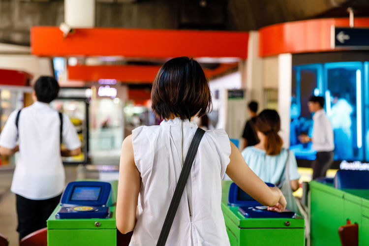 Woman scanning train ticket to entrance gate of sky train or subway, transportation concept
