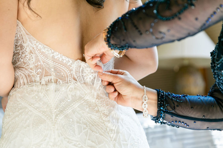 Midsection of bride getting wedding dress zipped up