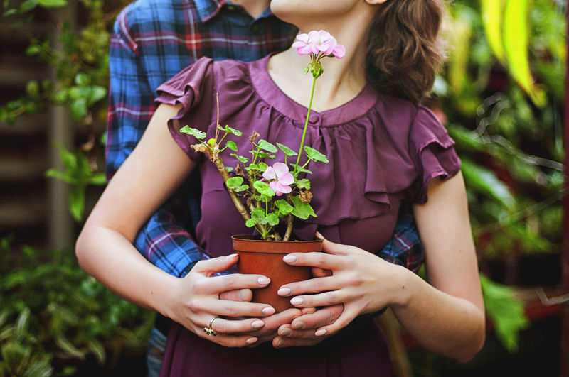 Midsection of woman holding purple flowering plants