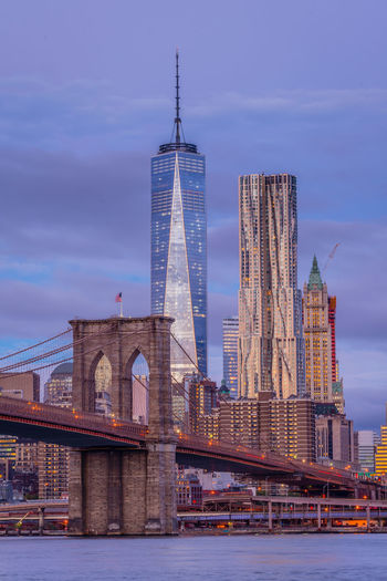 Low angle view of brooklyn bridge over river against one world trade center