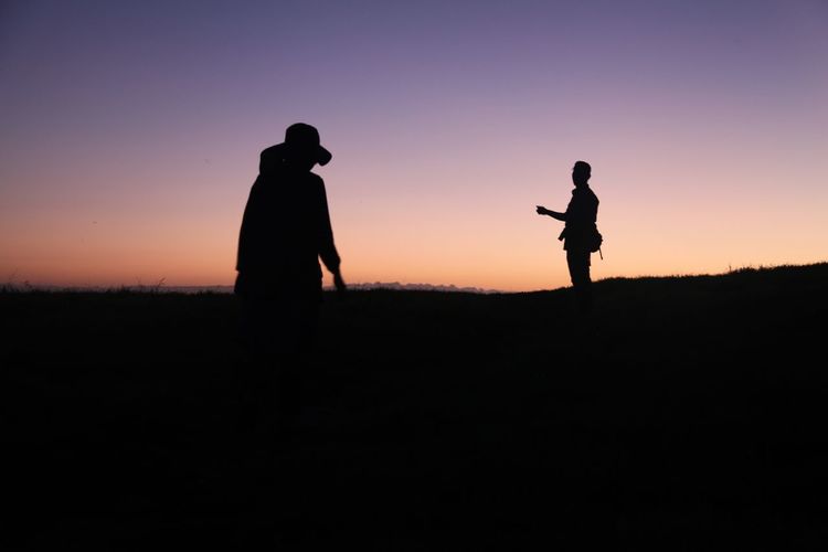 Silhouette of people on field at sunset