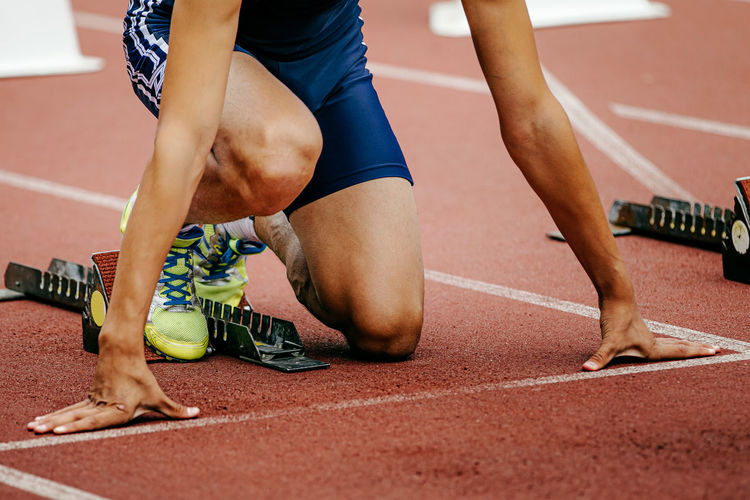 Low section of runner crouching on running track
