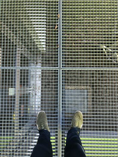 Low section of man standing on metal grate