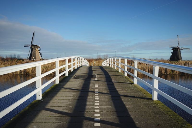 Footbridge over footpath against sky and ditch windmills