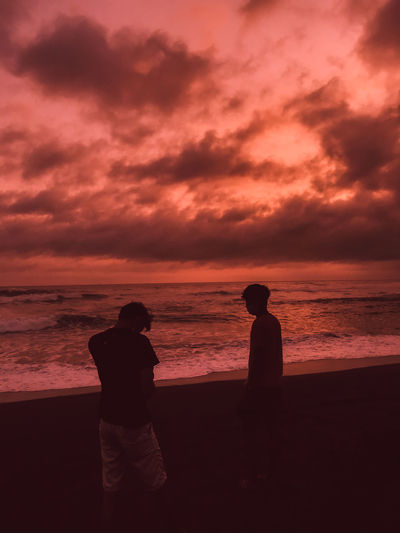 Silhouette man looking at sea against orange sky