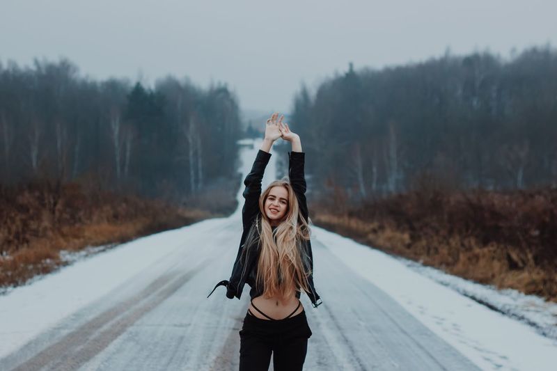 Young woman standing on snow covered road