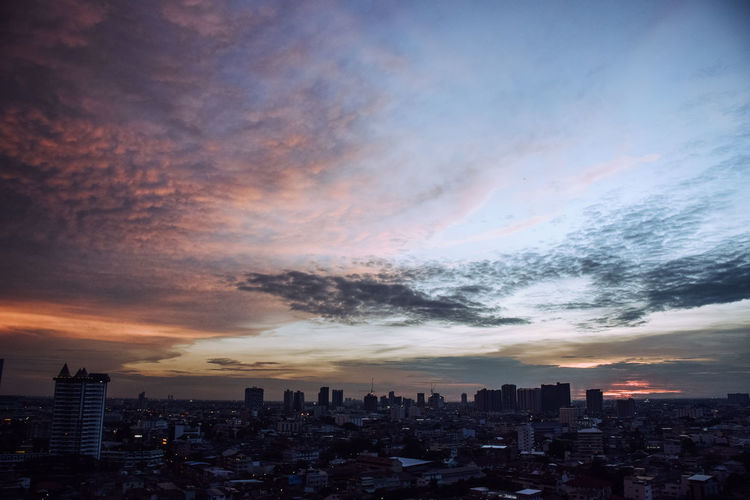 Aerial view of buildings in city against sky at sunset