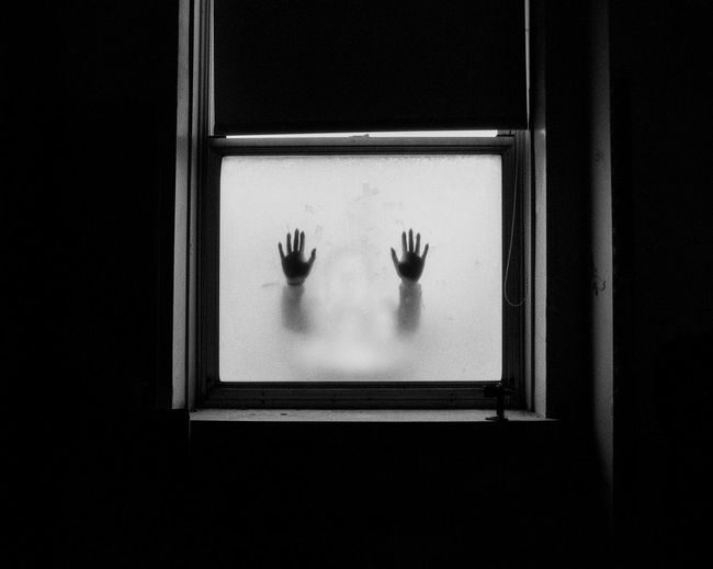 Silhouette of hands on frosted glass window