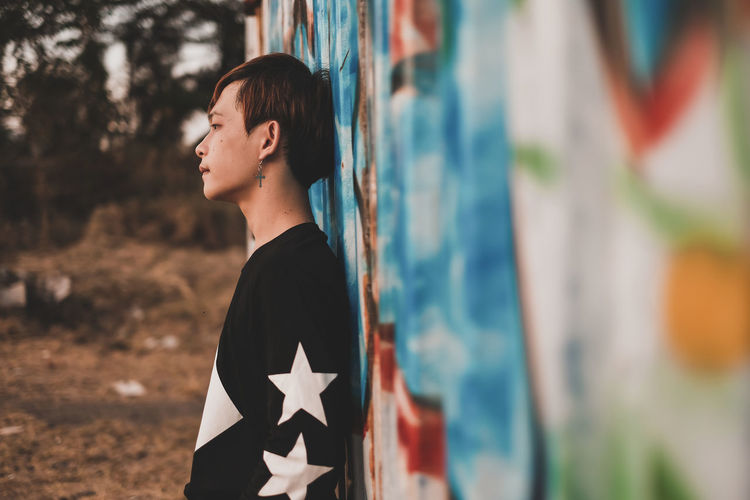Side view of teenage boy leaning on wall
