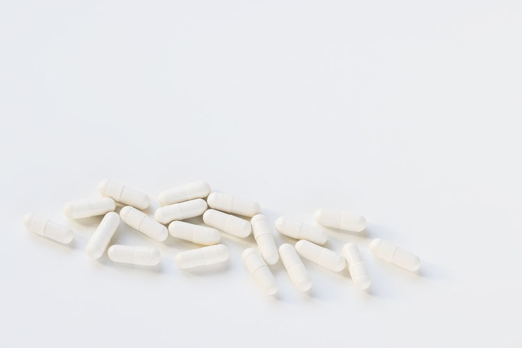Pills spilling from bottle against white background