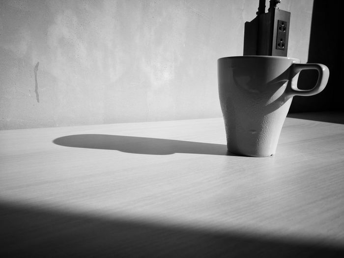 Close-up of coffee cup on table against wall at home