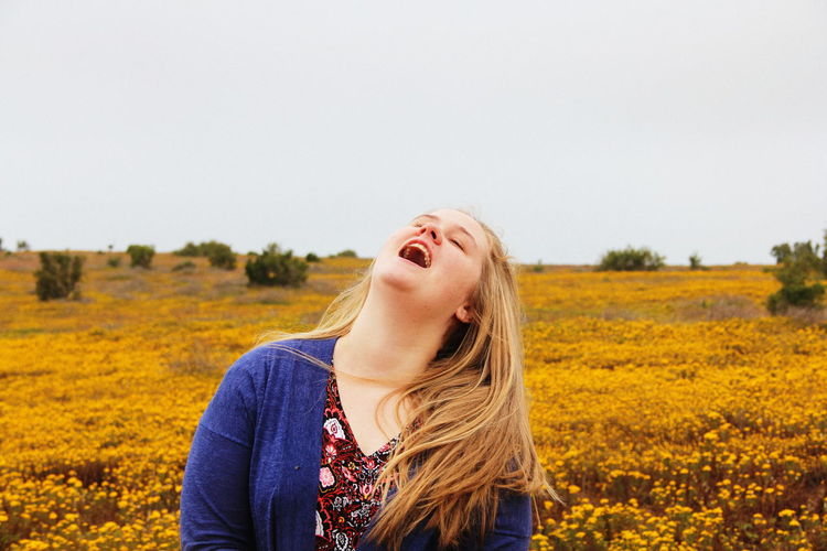 Woman with open mouth against yellow flowering plants