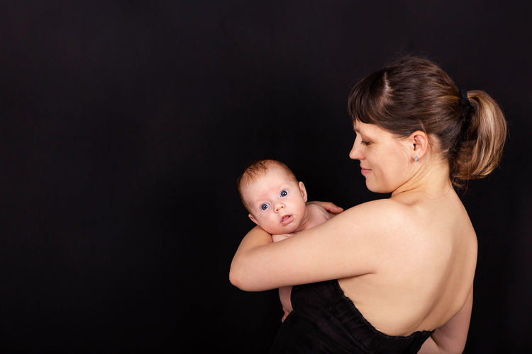Mother holding son against black background