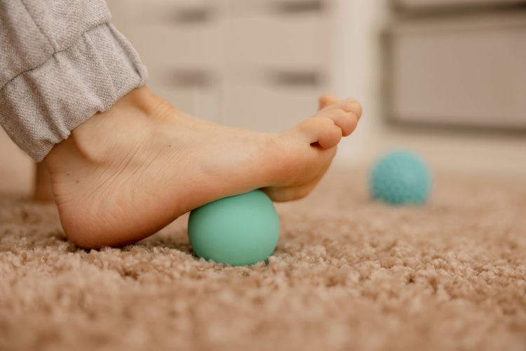 Woman doing flatfoot correction gymnastic exercise using massage ball. myofascial relaxation