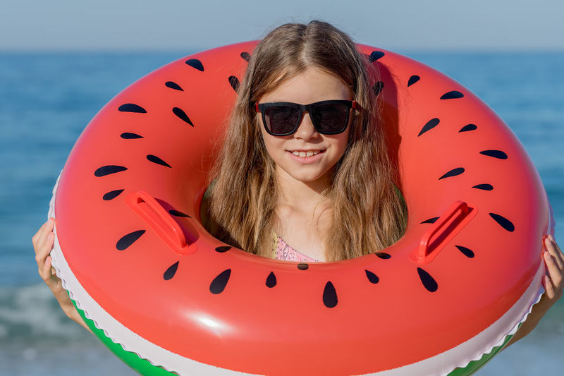 A girl in a swimsuit with an inflatable ring - a watermelon on the background of the sea. 