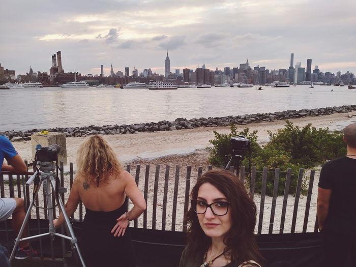 Portrait of woman with people looking at sea and city in background