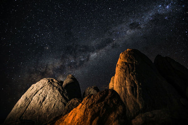 Low angle view of rock formations against star field at night