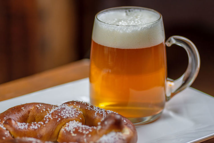 Large glass mug of beer and warm pretzel on table