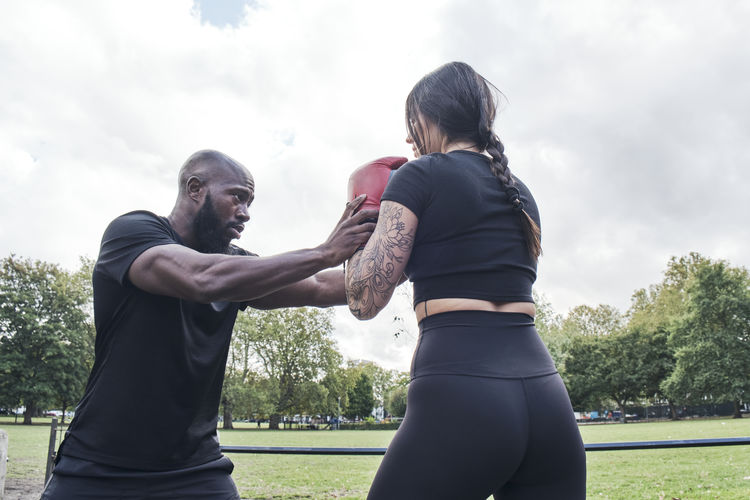 Strong brunette woman boxing outdoors with her personal coach.