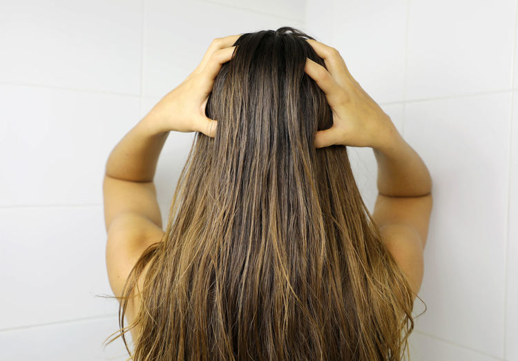 Young woman applying hair oil with her fingers. oiling hair before washing. hair care concept.