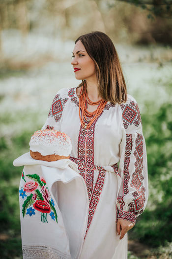 Woman holding cake standing outdoors