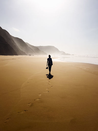 Silhouette of woman walking at beach on vacation