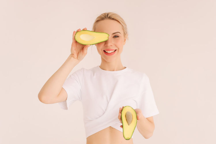 Young woman holding apple against white background