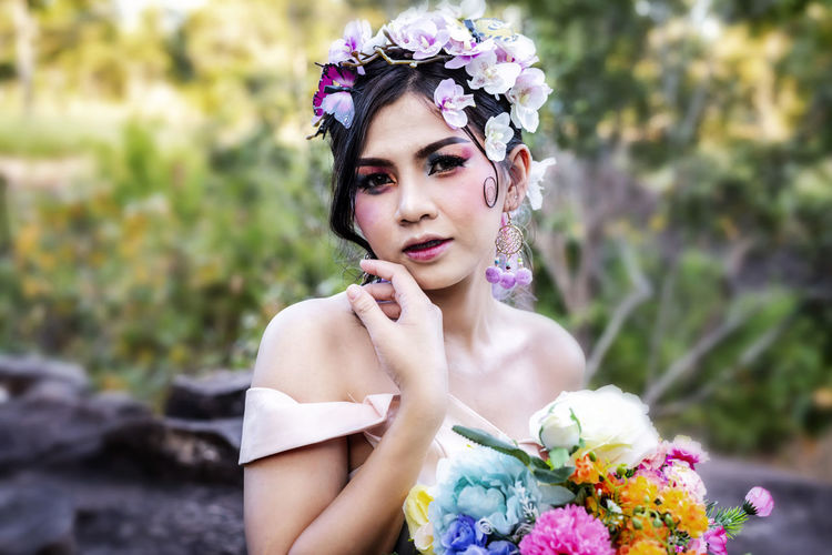 Portrait of beautiful bride with flowers at forest
