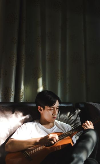Young man sitting and playing guitar 