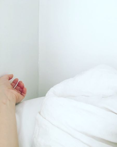 Cropped hand of woman lying on bed at home