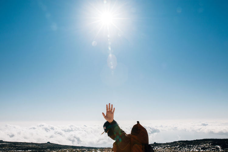 Man at mountain peak against blue sky on sunny day