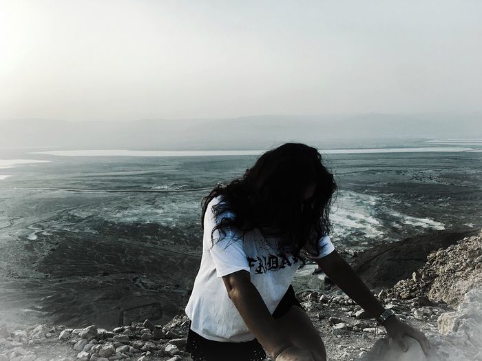 Woman standing at beach against sky