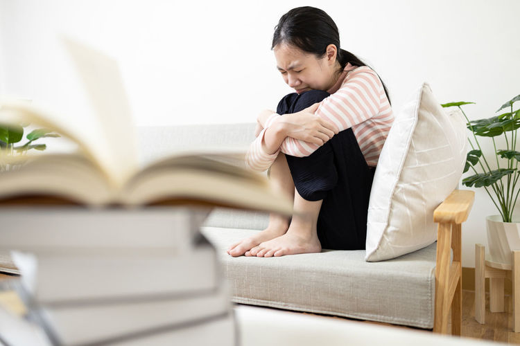 Side view of young woman reading book at home