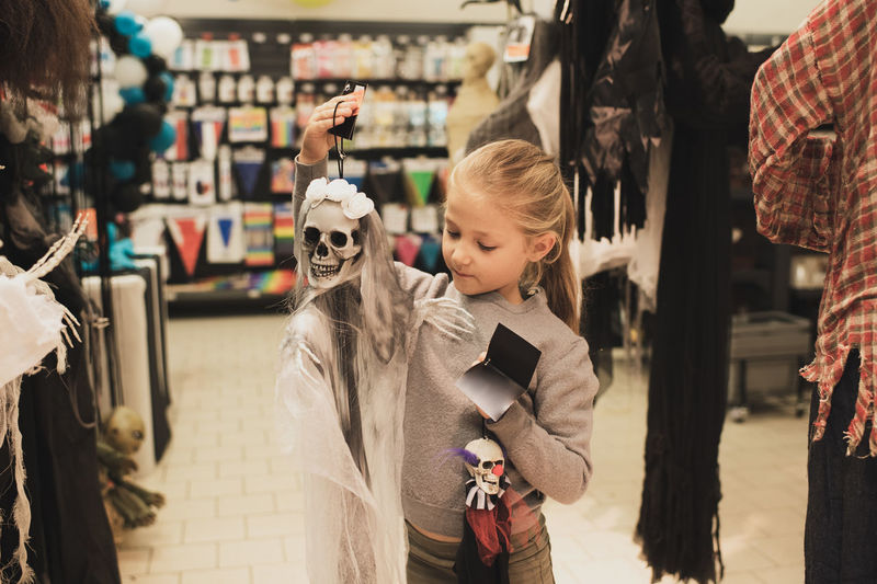 A girl chooses a skeleton toy in a store for halloween