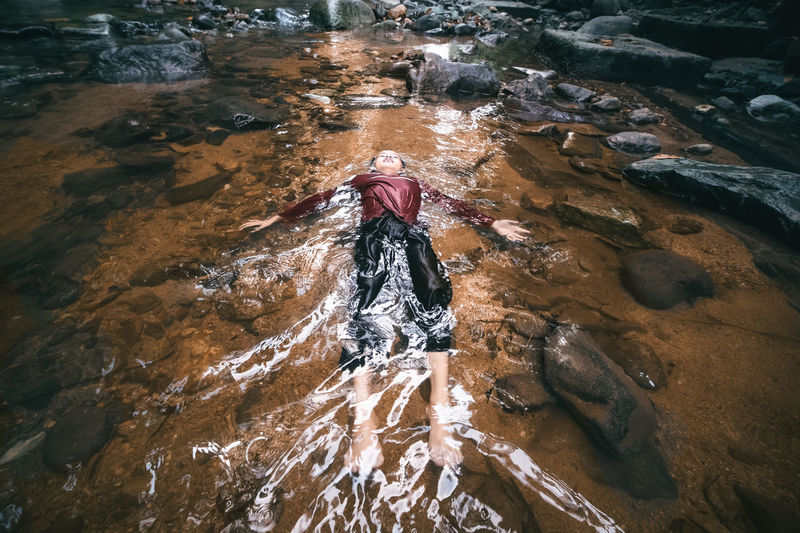 High angle view of boy lying in stream
