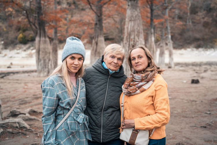Portrait of friends standing in forest during winter