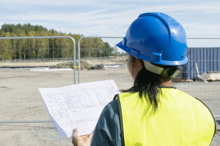 Woman holding blueprint at construction site