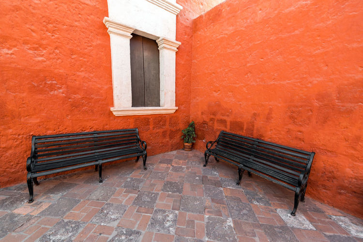 Empty benches against orange walls