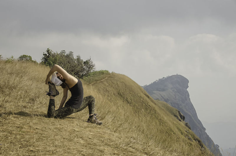 Side view of a man stretching backwards on landscape