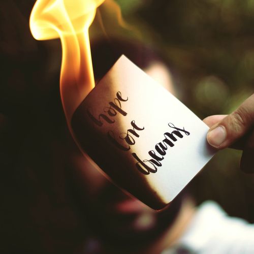 Cropped hand burning paper with message