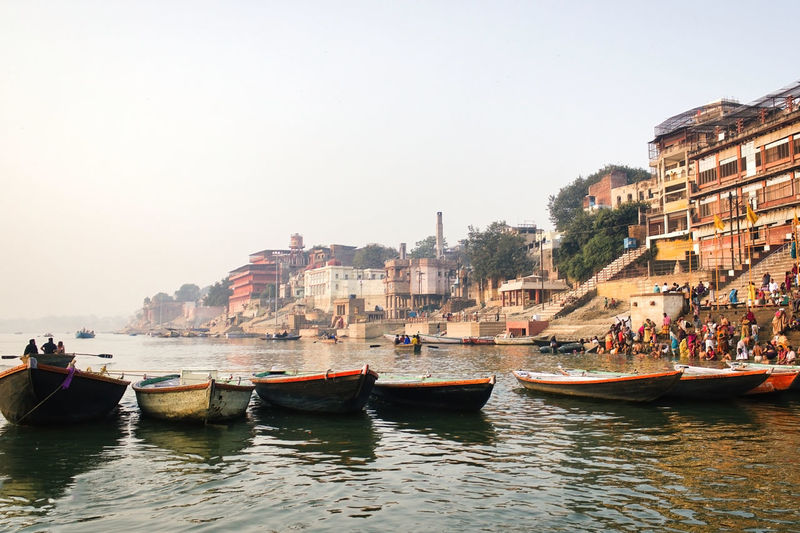 Bunch of colorful boats floating against a crowd of people tourist and pilgrims in kedar ghat ganges