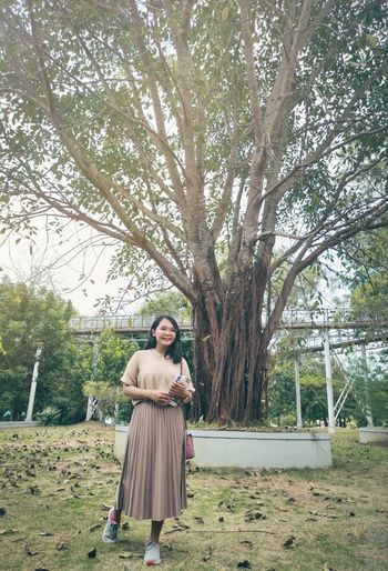 Full length of woman standing by tree