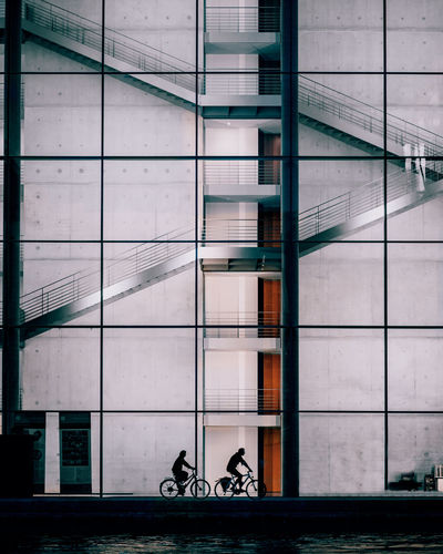 People riding bicycle on glass building