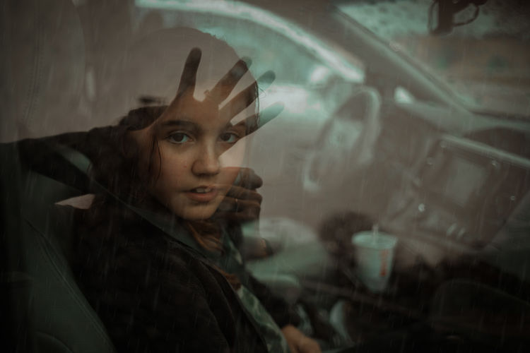 Portrait of girl seen through wet window