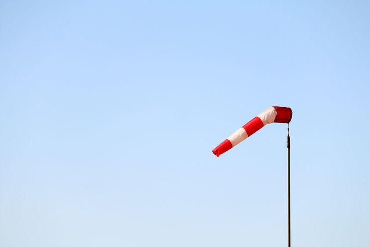 Low angle view of red flag against clear sky