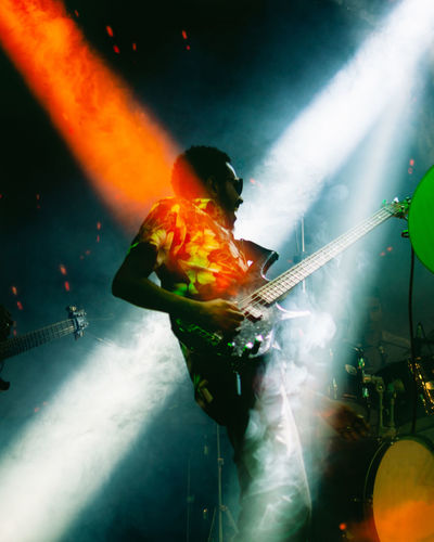 Lights shining on bass player at a concert