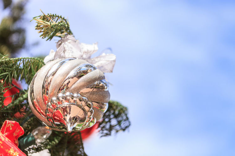 Low angle view of bauble hanging on christmas tree against sky