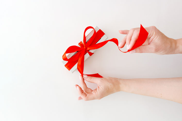 Gift box of chocolate candies with red decorative ribbon above white background.