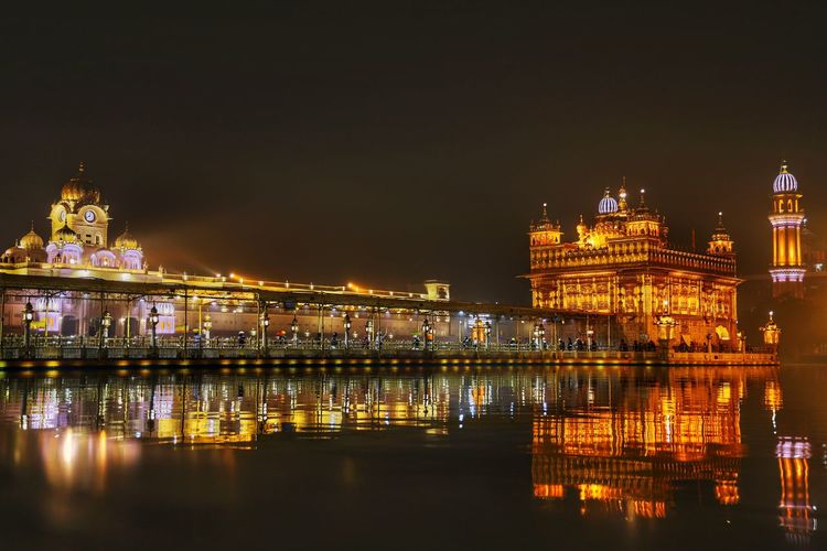 Illuminated buildings in city at night, golden temple amritsar 2021