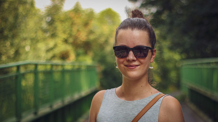 Portrait of smiling young woman wearing sunglasses in city